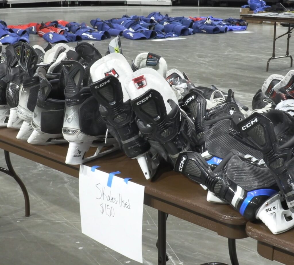 Multiple ice hockey skates on a table. 